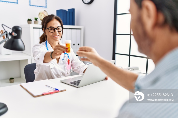 Middle age man and woman wearing doctor uniform prescribe pills at clinic