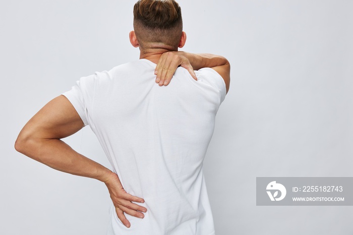 Man back pain neck and joints, bone and spine problems, inflammation and trauma, in white T-shirt on white isolated background, copy space