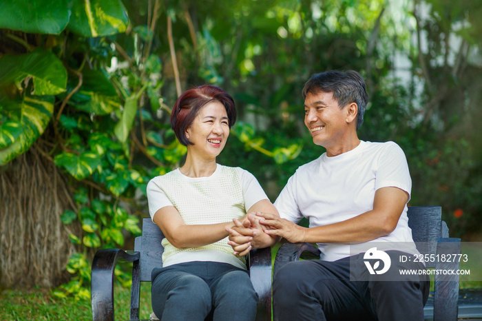 Middle aged couple relax sitting on bench in backyard.