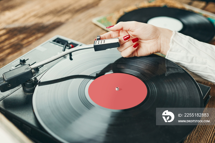 Young woman listening to music from vinyl record player. Playing music on turntable player. Female enjoying music from old record collection at home