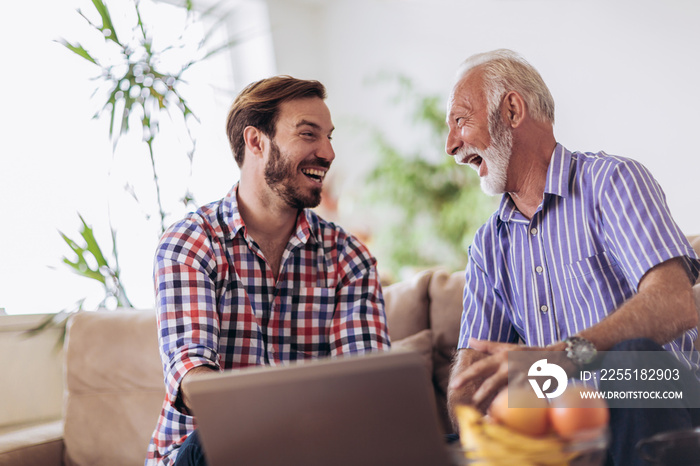 Adult Son Helping Senior Father With Computer At Home