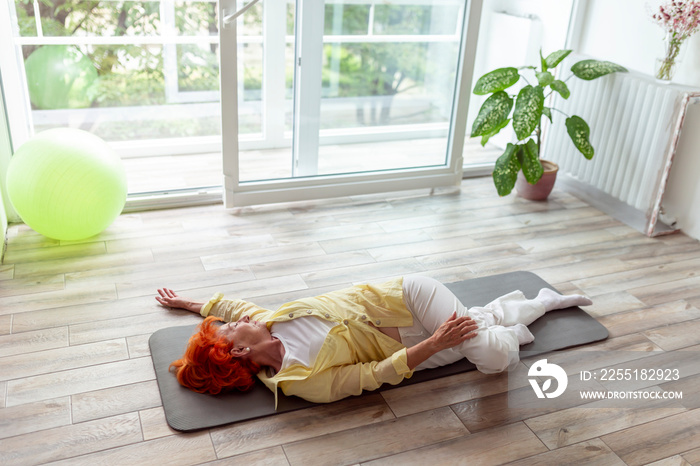 Senior woman doing spinal twist yoga exercise