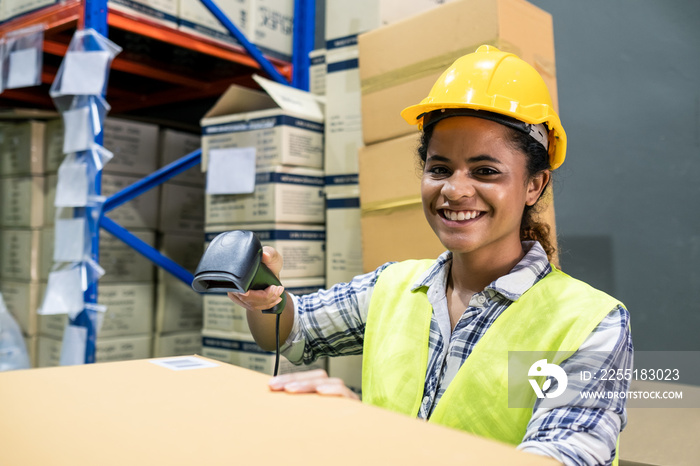 Young smiling black woman worker in safety helmet in factory warehouse