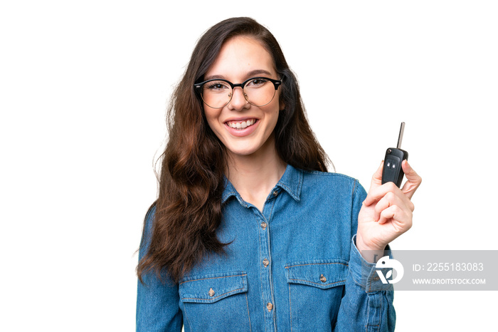 Young caucasian woman holding car keys over isolated background smiling a lot