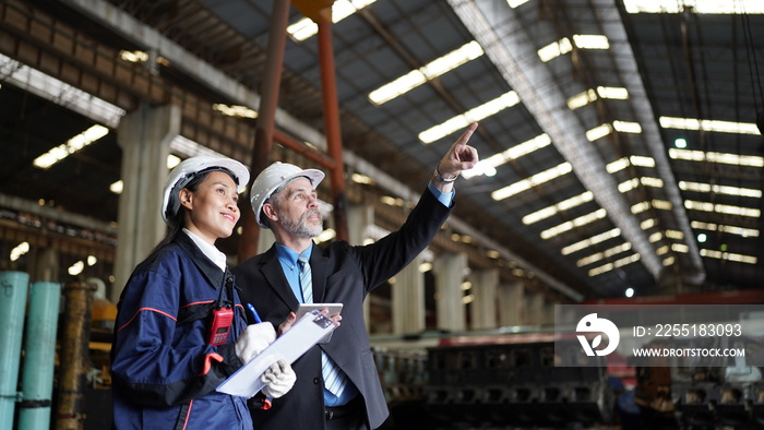 Factory manager or businessman and female engineer in factory. elegant man inspecting factory in industry plant background.