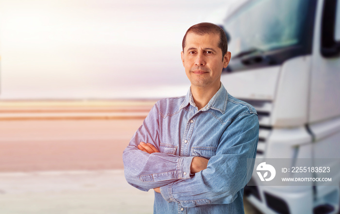 Portrait of caucasian trucker with arms crossed standing by his truck vehicle.