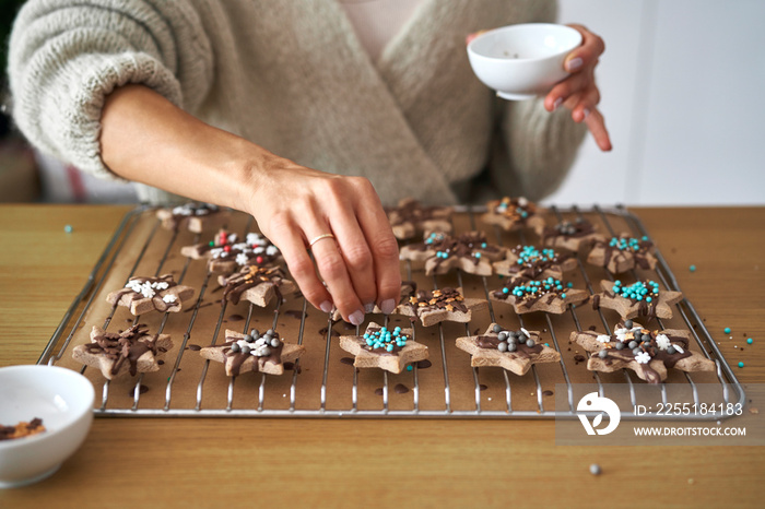 Close up of caucasian woman decorating sweet cookies at home during the Christmas