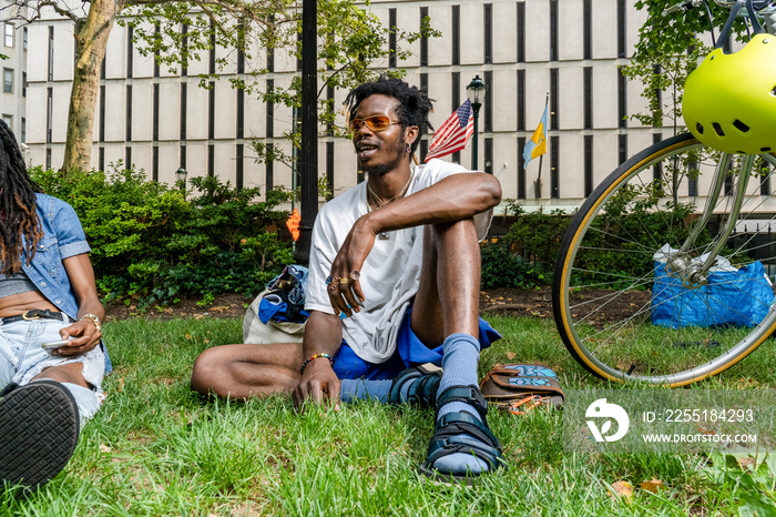 USA, Stylish young friends sitting on grass in park