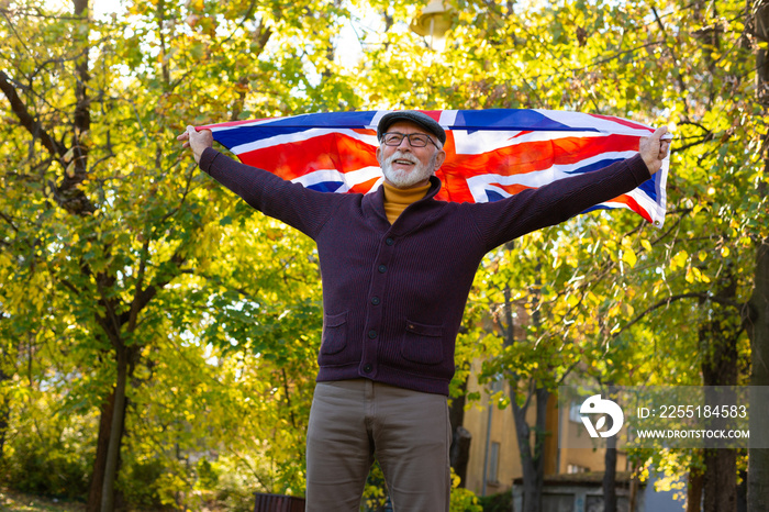 Senior man walking in park with a Britain flag