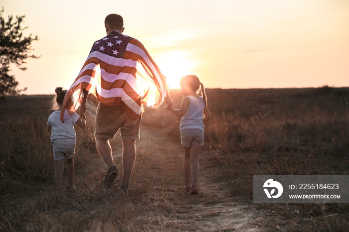 A happy family with an American flag at sunset.