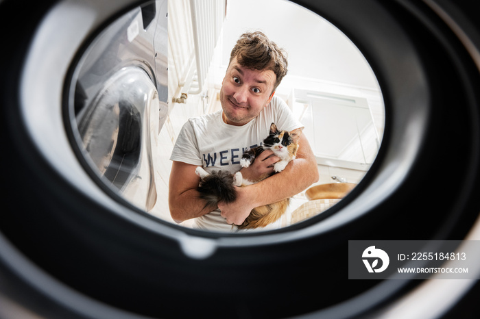 Man with cat view from washing machine inside. Male does laundry daily routine.