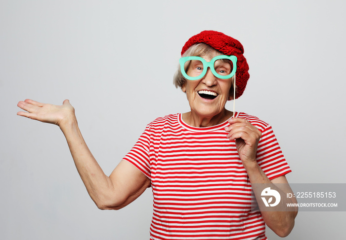 lifestyle, emotion and people concept: funny grandmother with fake glasses, laughs and ready for party