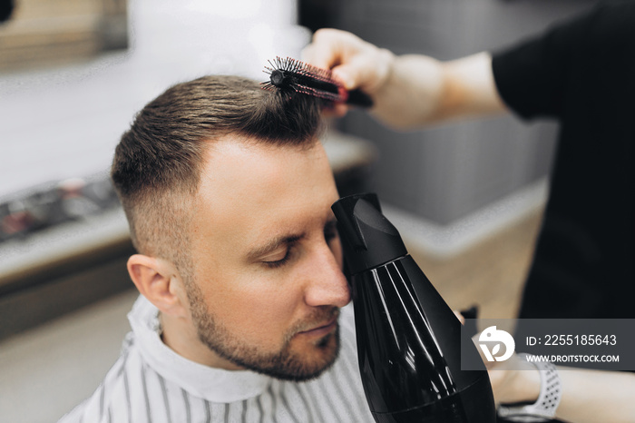 Male barber drying hair of hipster