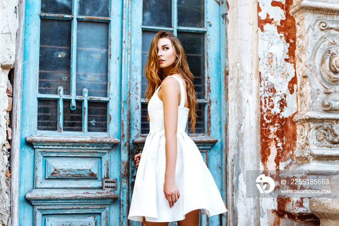 Beautiful girl in a white dress near a blue door