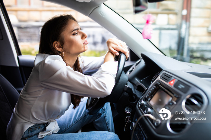 Feeling tired. Attractive young woman sleeping on wheel inside car.