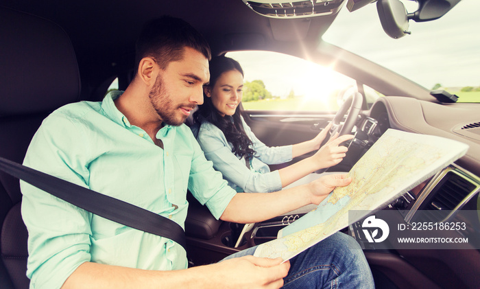 leisure, road trip, travel and people concept - happy man and woman driving in car and searching location on map