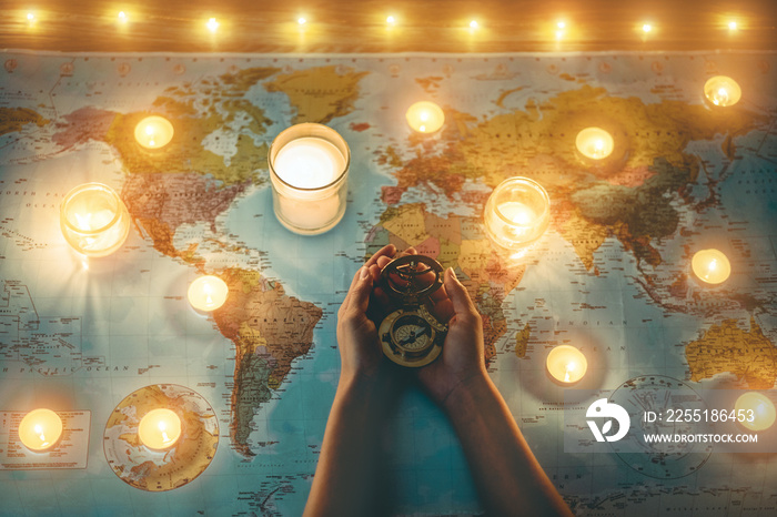 Young woman planning world tour with vintage travel map - Traveler girl using old compass with candles in background - Wanderlust, globetrotter trends and holiday concept - Focus on hands