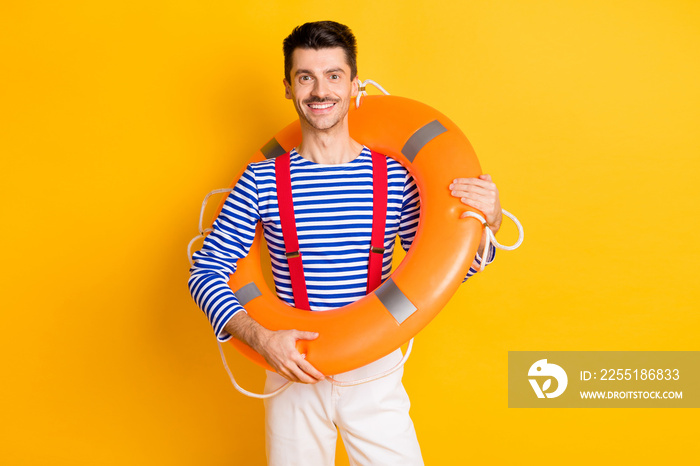 Photo of young happy positive cheerful good mood man sailor with big buoy on shoulders isolated on yellow color background