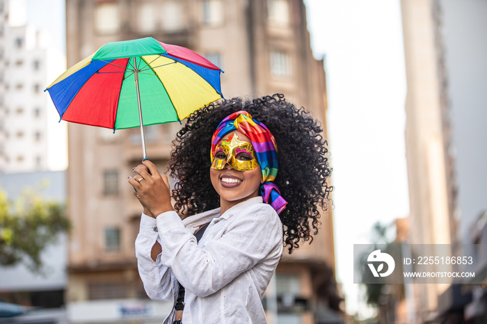 Young curly hair woman celebrating the Brazilian carnival party with Frevo umbrella on street.