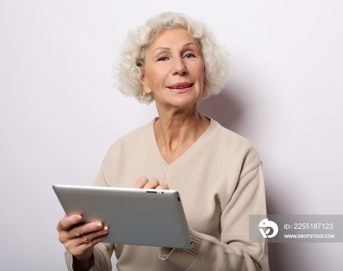 lifestyle, technology and people concept: Happy mature woman using a tablet, communicates with children and grandchildren