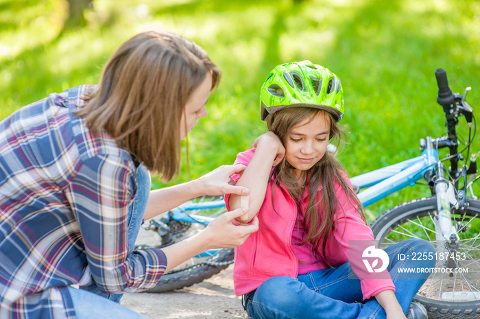 Mother puts a bandage on a wound to little girl, who fell off his bicycle