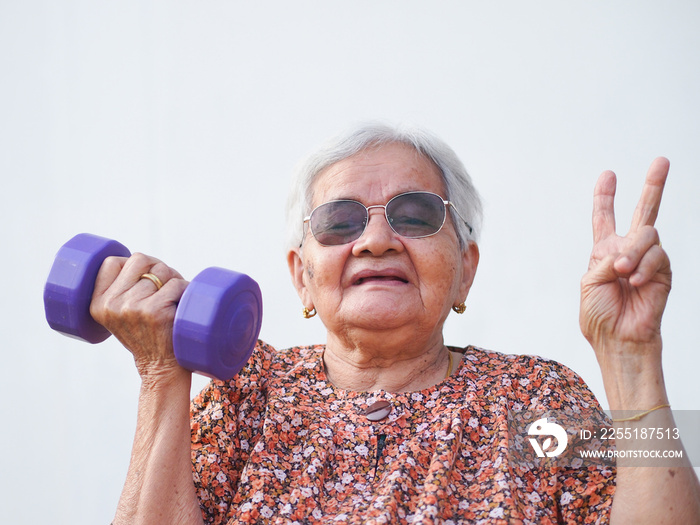 Strong Asian grandmother lifts dumbbells. Elder fit healthcare concept.