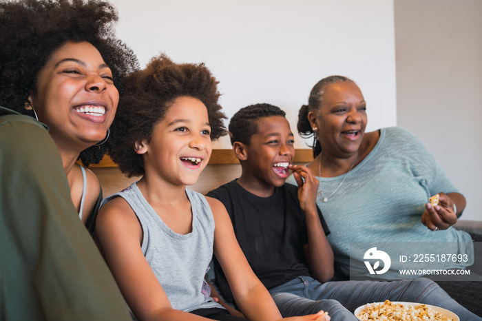 Grandmother, mother and children watching a movie at home.