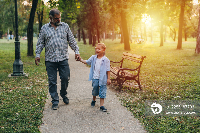 boy with his grandfather walking in the city park