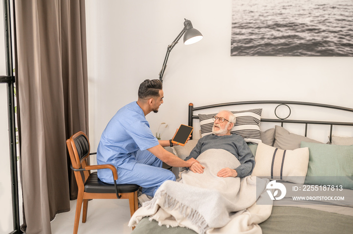 Doctor checking the health condition of a bedridden aged man