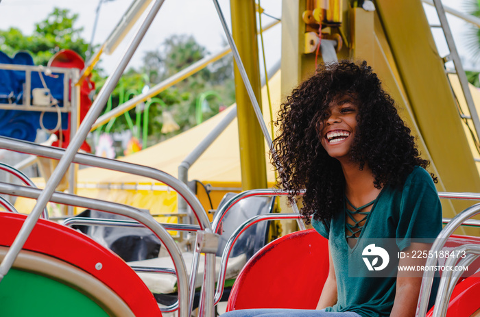 young girl of black color, laughing hair in ferris wheel, sitting enjoying a summer day, lifestyle portrait