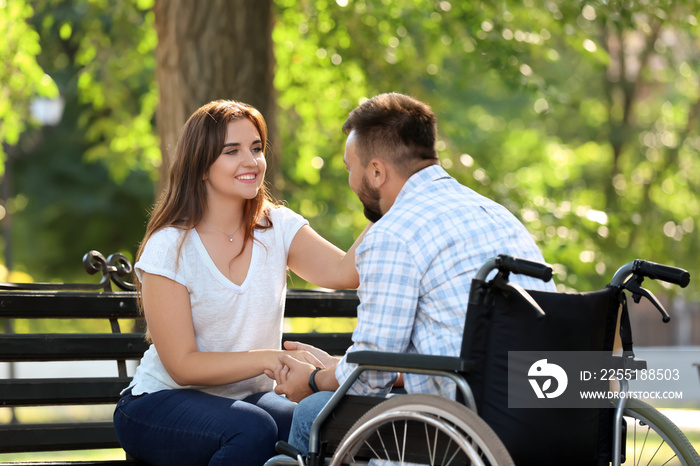 Young man in wheelchair with his wife outdoors