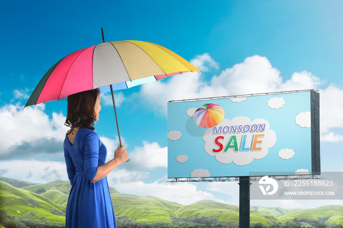 Happy asian woman looking at monsoon sale sign on billboard