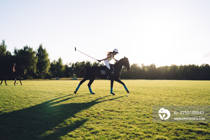 Female jockey riding horse on meadow during polo training