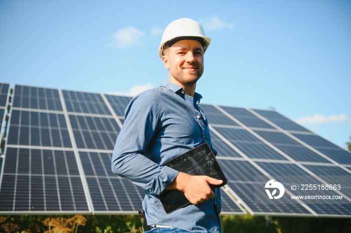 The portrait of a young engineer checks with tablet operation with sun, cleanliness on field of photovoltaic solar panels. Concept: renewable energy, technology, electricity, service, green power