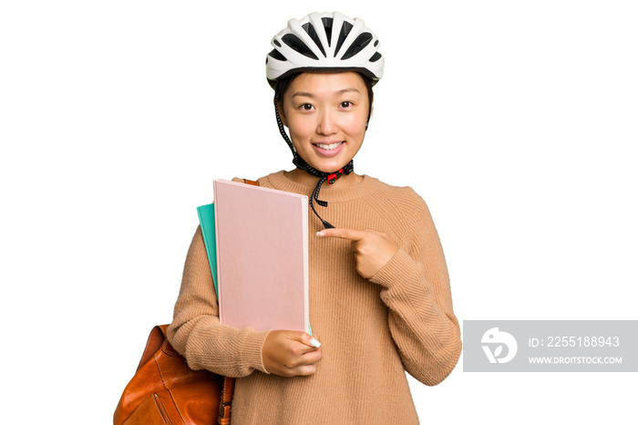 Young student asian woman wearing a bike helmet isolated on green chroma background smiling and pointing aside, showing something at blank space.