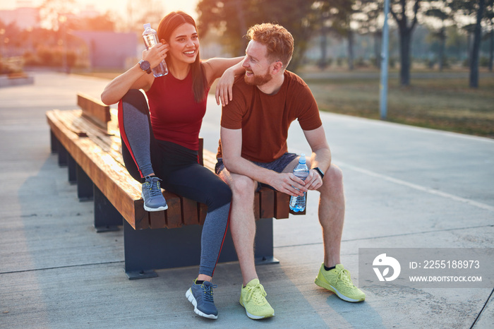 Modern couple making pause in an urban park during jogging / exercise.