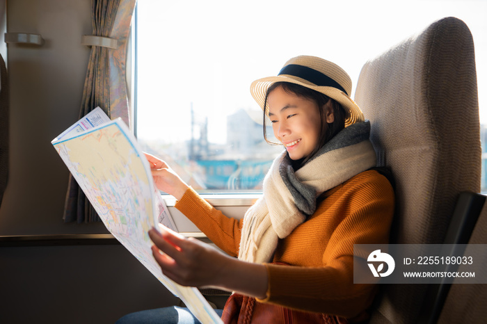 Young Asian one woman traveller in transport on Japan train looking in ordinary map for properly destination, travel on public transport by owns way selection in Kyoto, Japan..