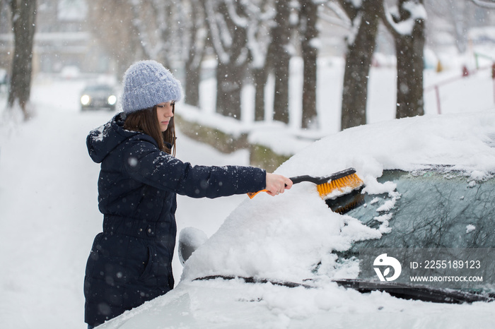 Woman removing snow from car windshield