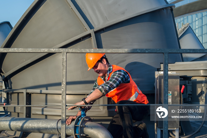 worker in industry.  worker open valve of cooling tower on blue sky background. worker opening butterfly valve on top of cooling Tower. engineer check valve on cooling tower.