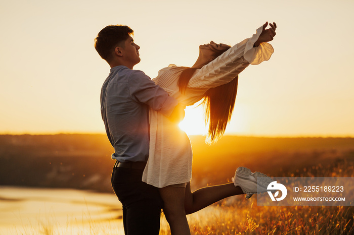 Couple romantic in love at beach sunset. Happy young couple embracing enjoying sunset during travel holidays vacation.