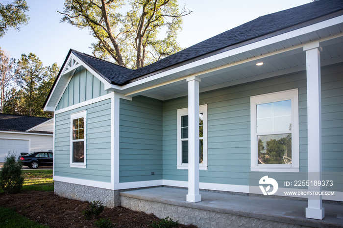 Front view of a brand new construction house with blue siding, a ranch style home with a yard