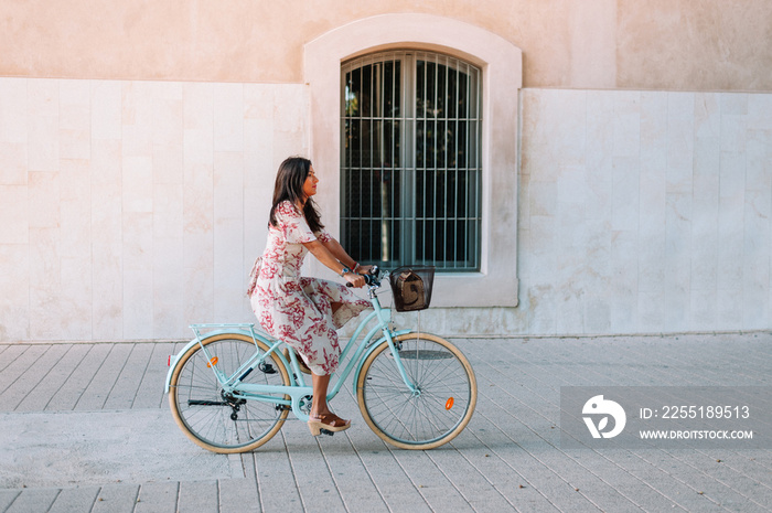 Full body portrait of a beautiful stylish woman riding with retro bicycle outdoors on the industrial urban background