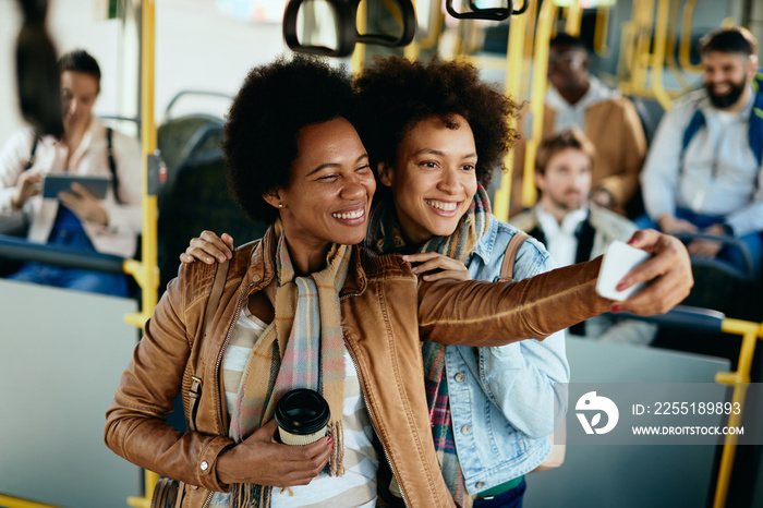 Happy black women having fun while taking selfie in a bus.