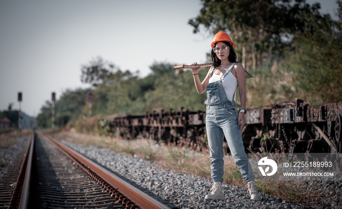 Portrait beautiful woman coal worker showed working near railway station with orange helmet and shoveling coal with twilight sky background.