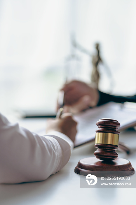 Business lawyers working on law in a courtroom help clients read legal documents and study information about court cases, along with a justice scale and hammer.