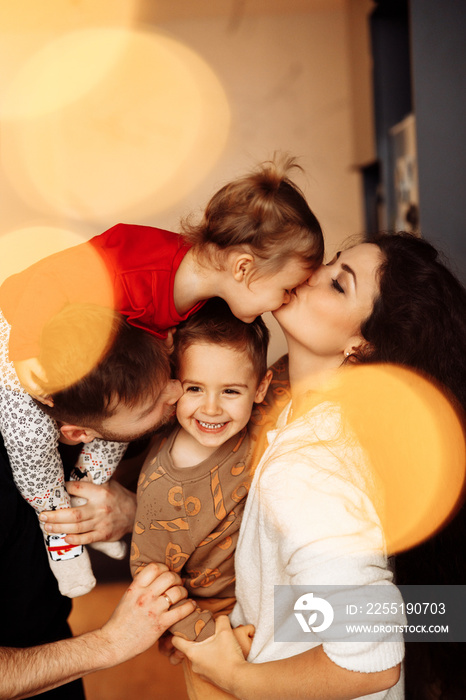 Portrait of overjoyed parents with little kids at home, smiling and cuddling. Happy family with adorable daughter and joyful son spend time together. Fatherhood and motherhood concept