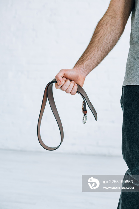 cropped view of man holding leather belt at home