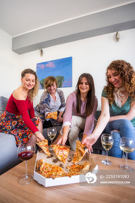 Four female friends grabbing pizza slice