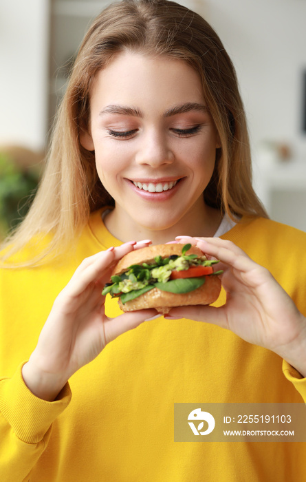 Young woman with tasty vegan burger at home, closeup