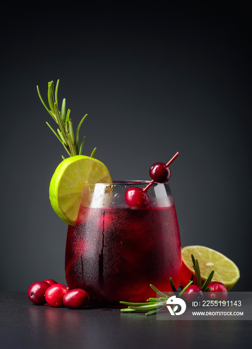 Cranberry cocktail garnished with berries, lime, and rosemary.